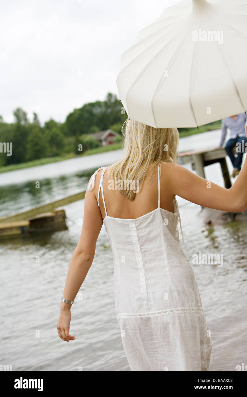 A woman with an umbrella walking ont the beach, Ljustero, Stockholm archipelago, Sweden. Stock Photo