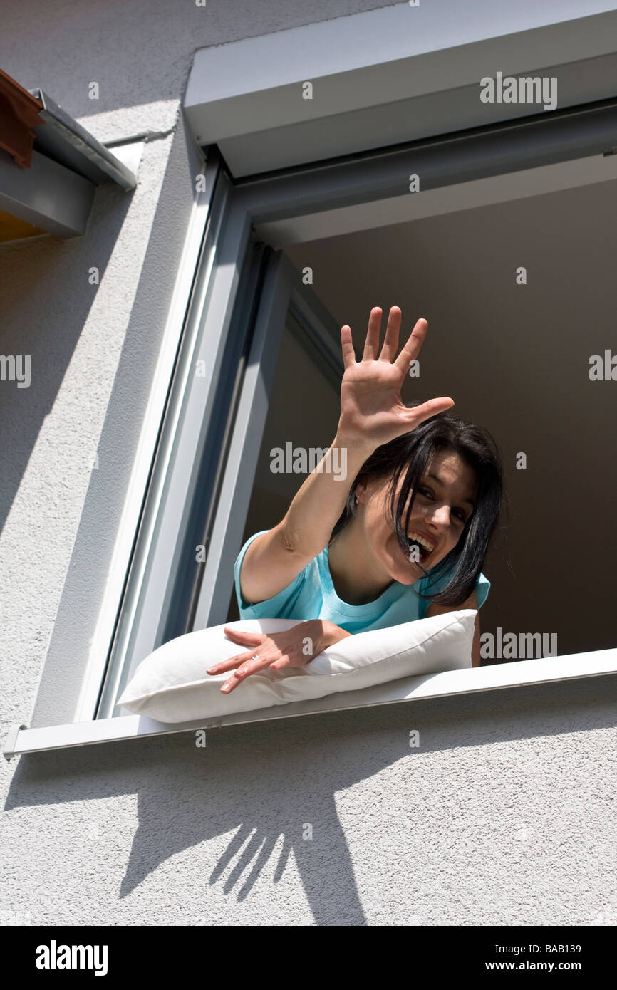 Woman wave out of a window - Frau winkt aus einem Fenster Stock Photo