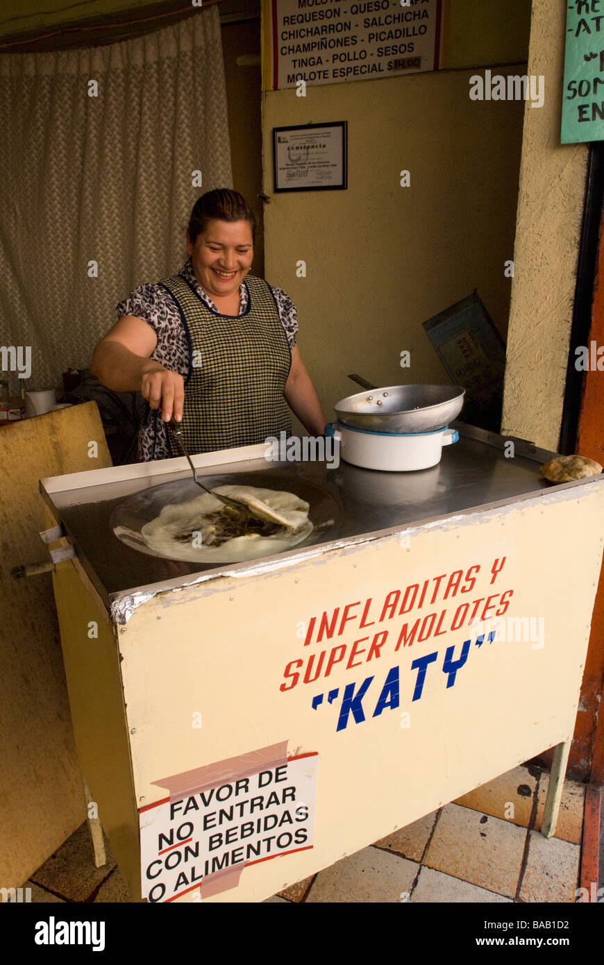 Mexican woman cooking cornmeal infladitas in hot oil in a small restaurant.  Puebla, Mexico Stock Photo