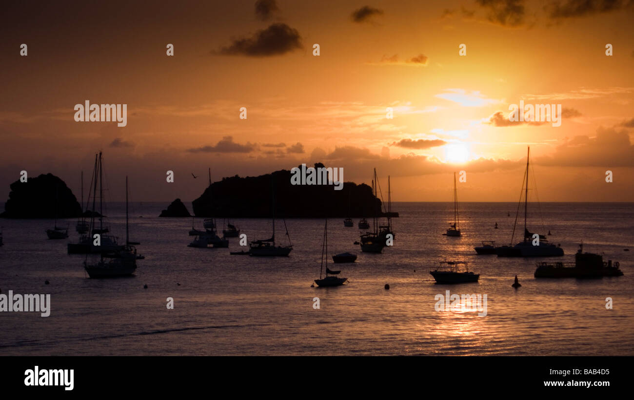 Sun sets behind small boats moored off Gustavia port St Barts Stock Photo