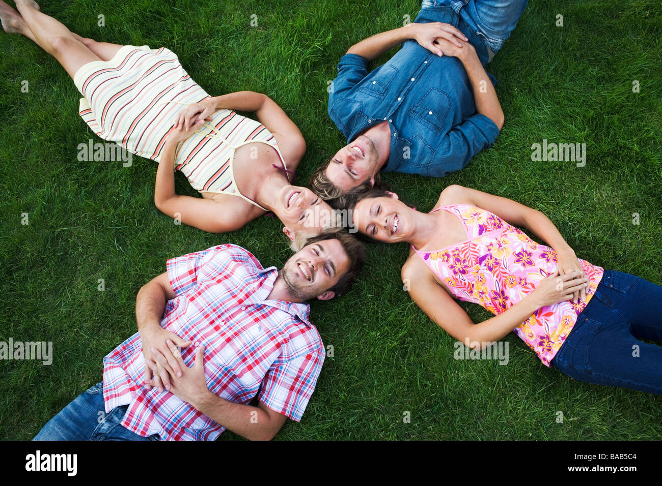 Four people lying on a lawn, Sweden. Stock Photo