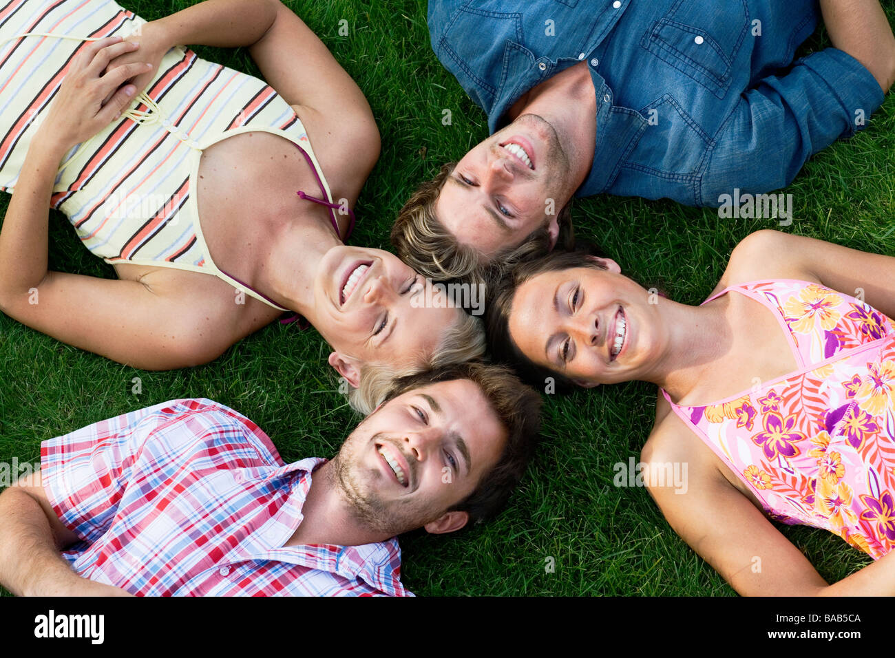 Four people lying on a lawn, Sweden. Stock Photo