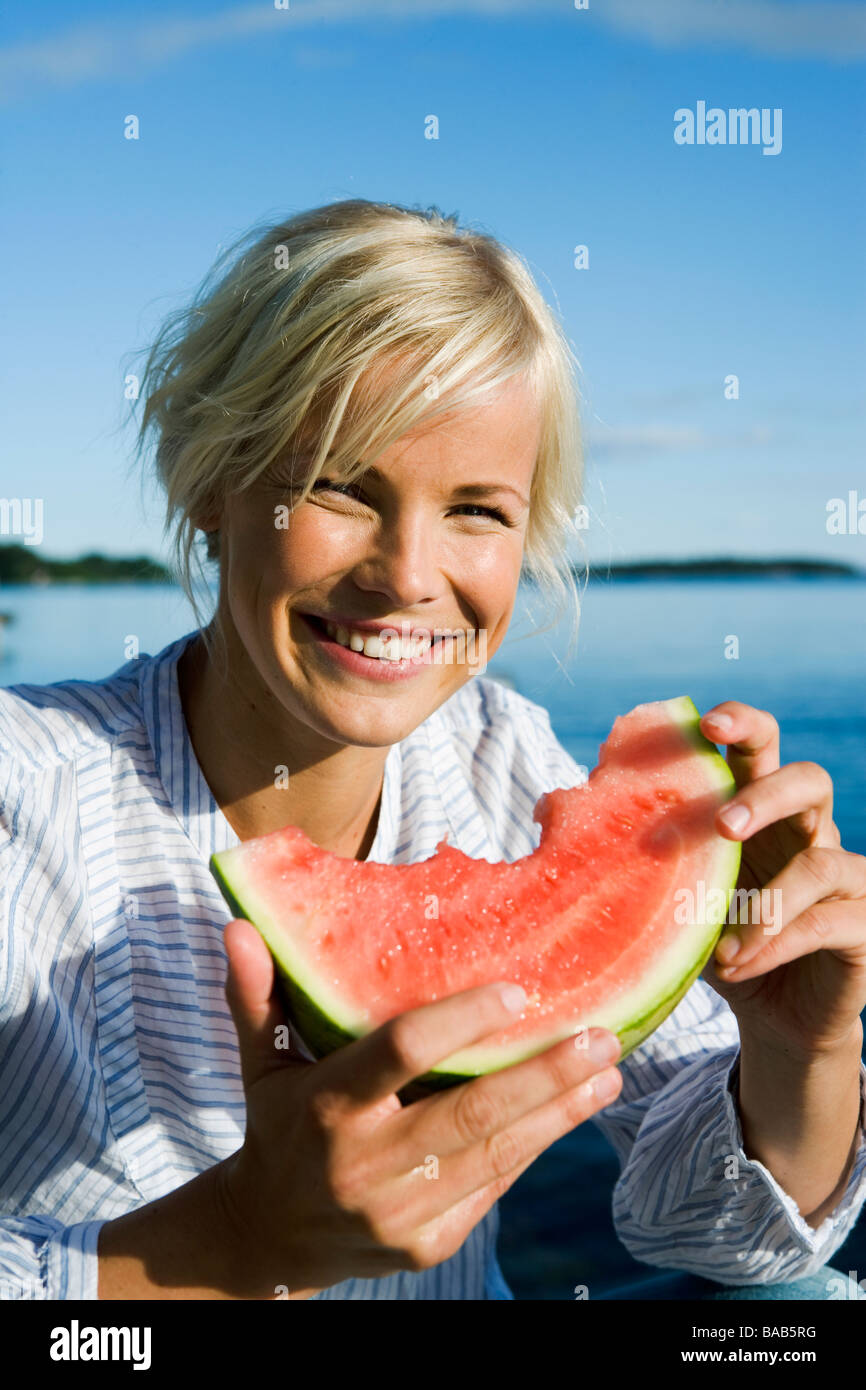 A woman eating a watermelon by the sea in the archipelago of Stockholm