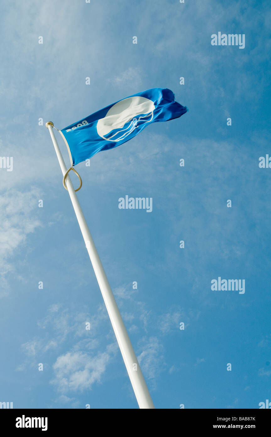 A Blue Flag flying against a blue sky with some cloud cover on the beach at  Brighton, england Stock Photo
