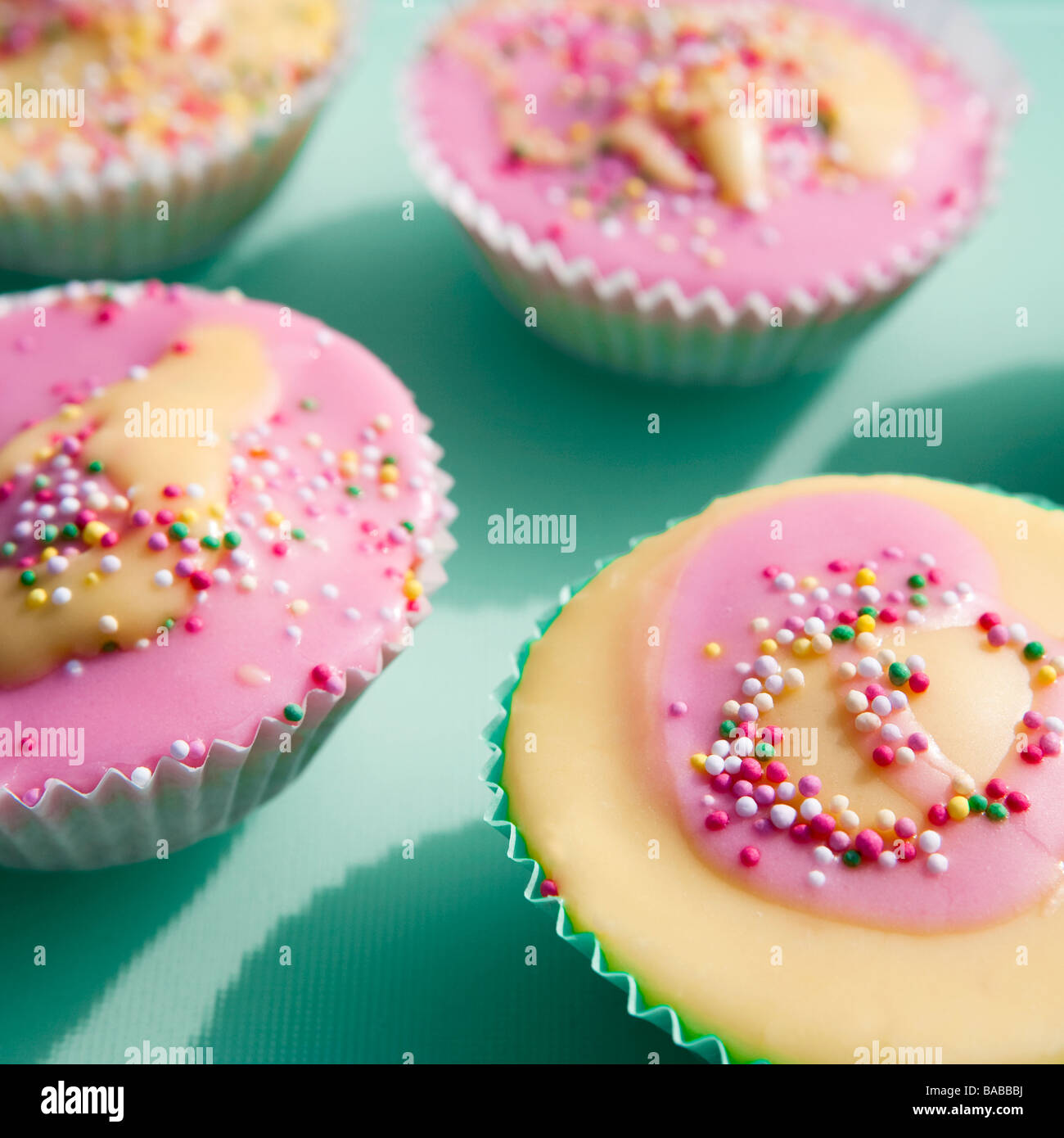 Home made cup cakes decorated with pink and yellow icing and hundreds n thousands. Also called fairy cakes. Stock Photo
