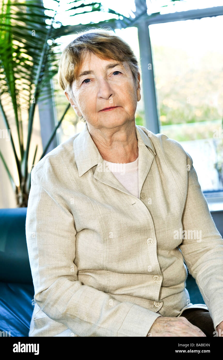 Sad elderly woman sitting on a couch indoors Stock Photo - Alamy
