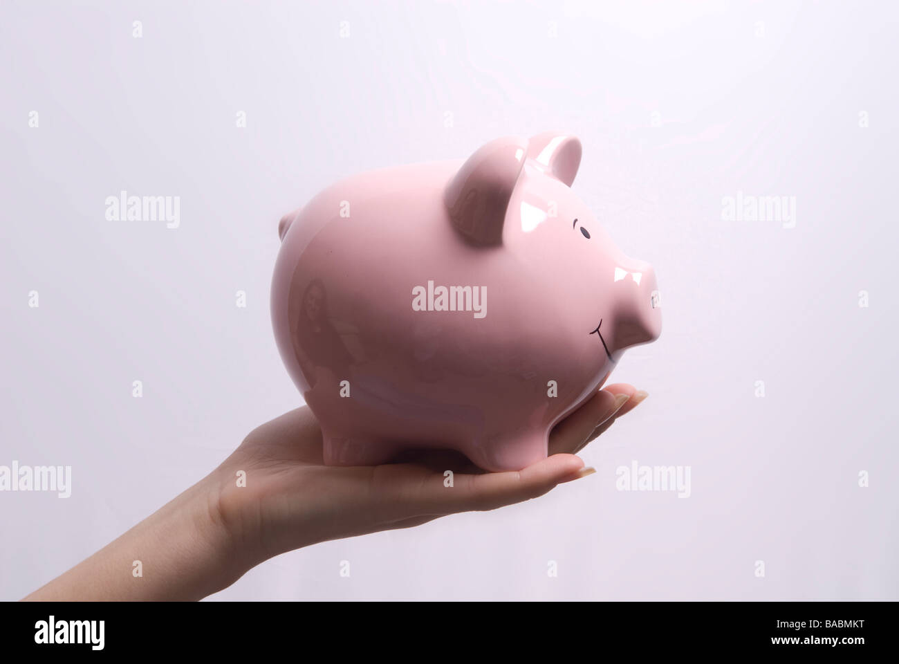 Woman's hand holding a pink piggy bank Stock Photo - Alamy