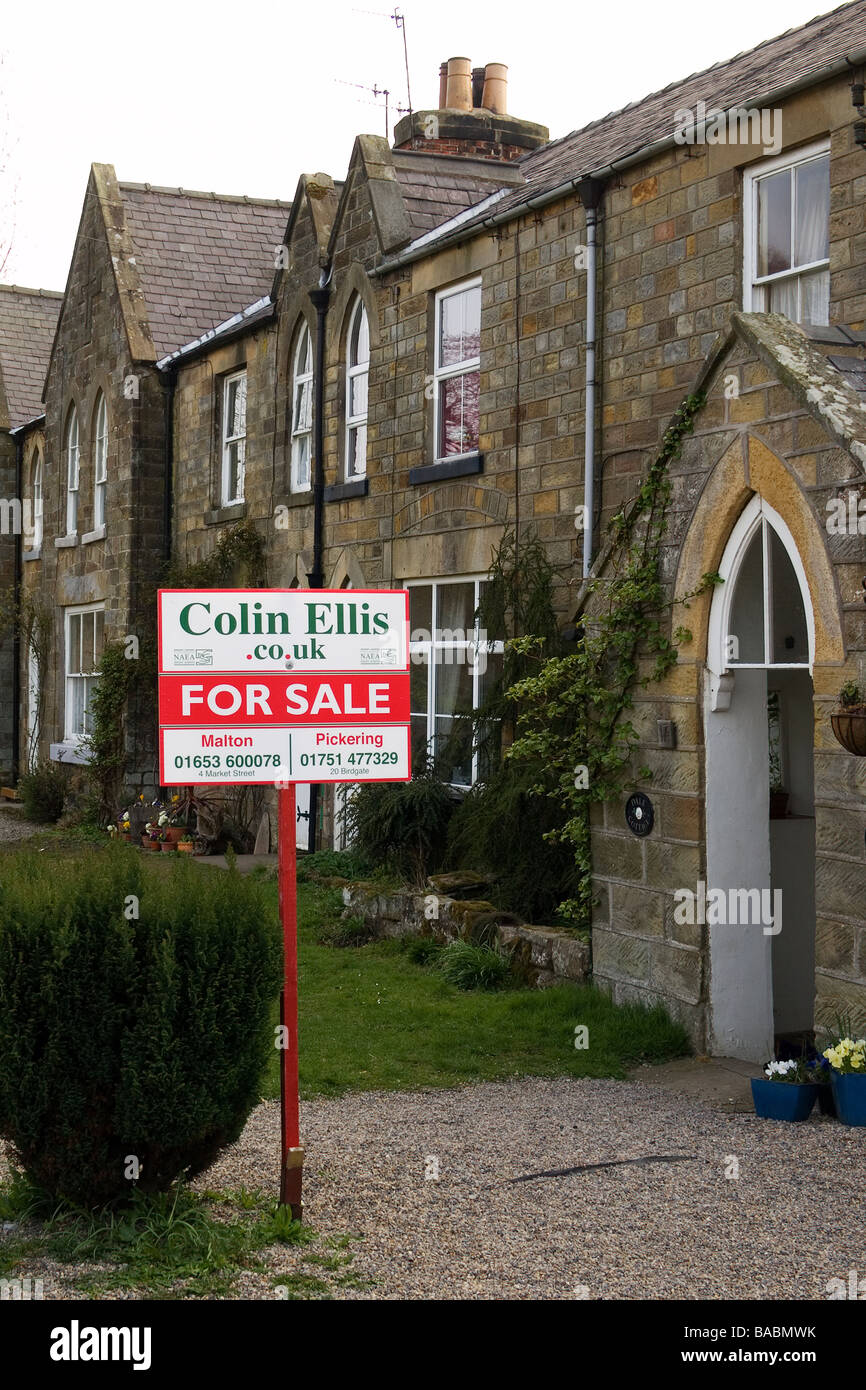 A traditional stone cottage with an Estate Agents sign board at Rosedale Abbey North Yorkshire