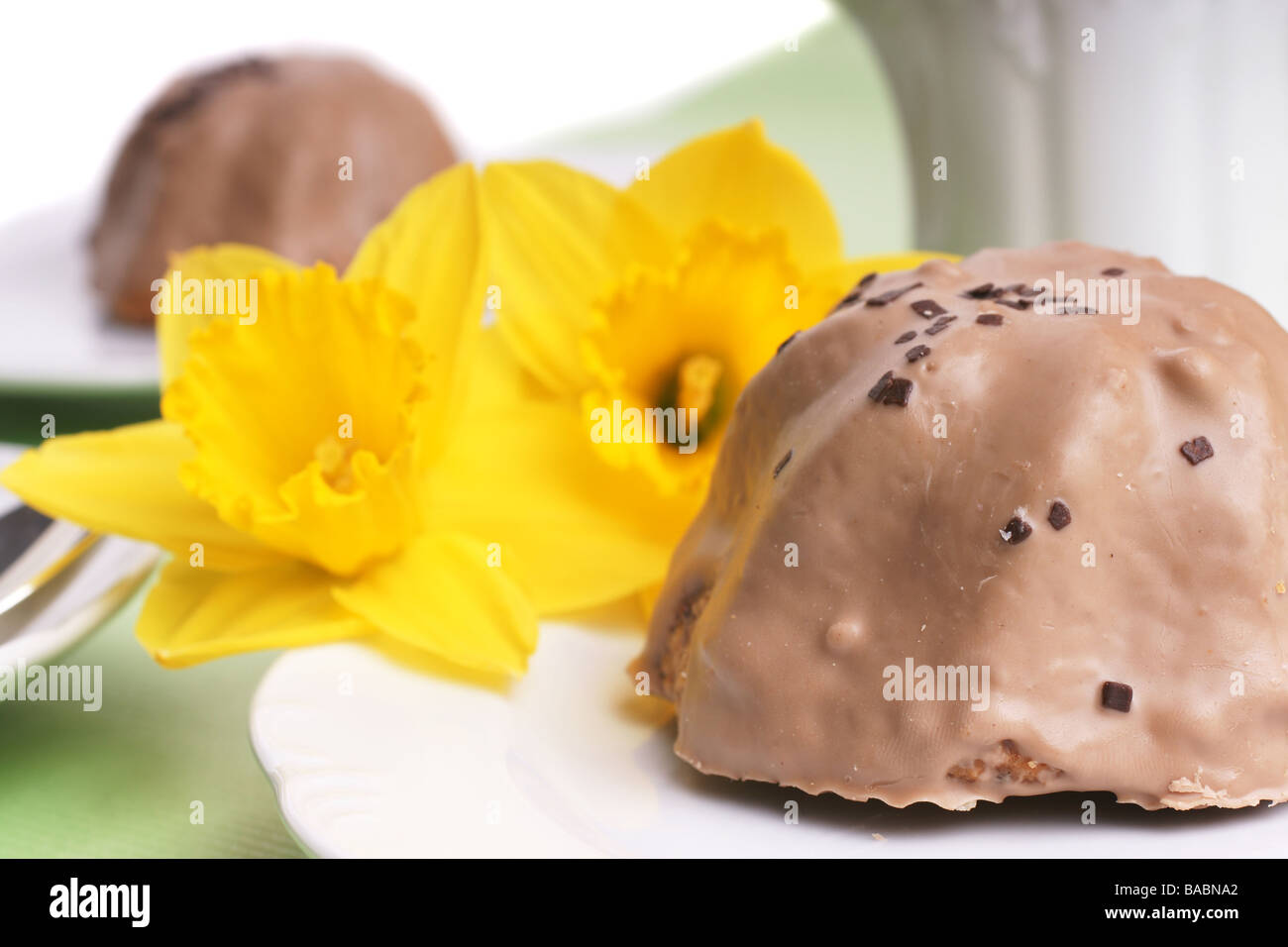 Two little cupcakes with chocolate frosting and daffodils Stock Photo