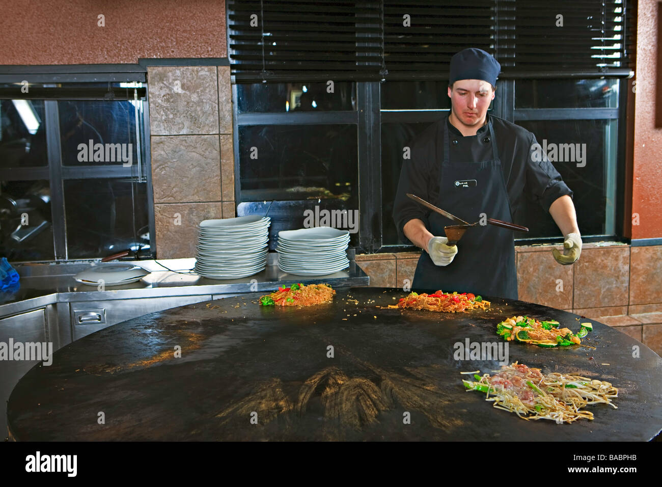 Chef performing with utensils while preparing meals at the Mongolie Grill World Famous Stirfry Restaurant in Whistler Village. Stock Photo