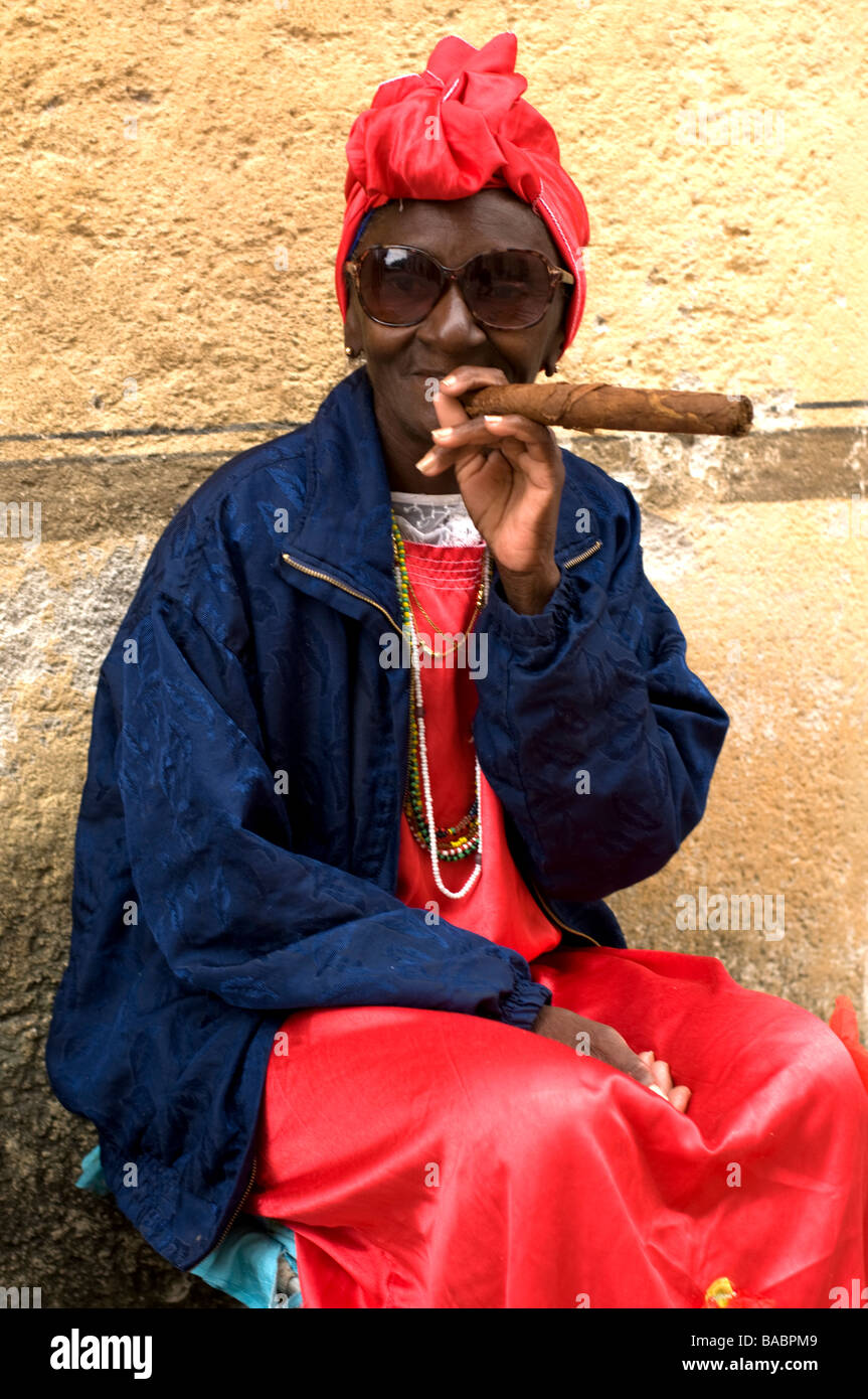 Elderly woman in a red headdress smokes a large cigar in Havana Vieja. Stock Photo