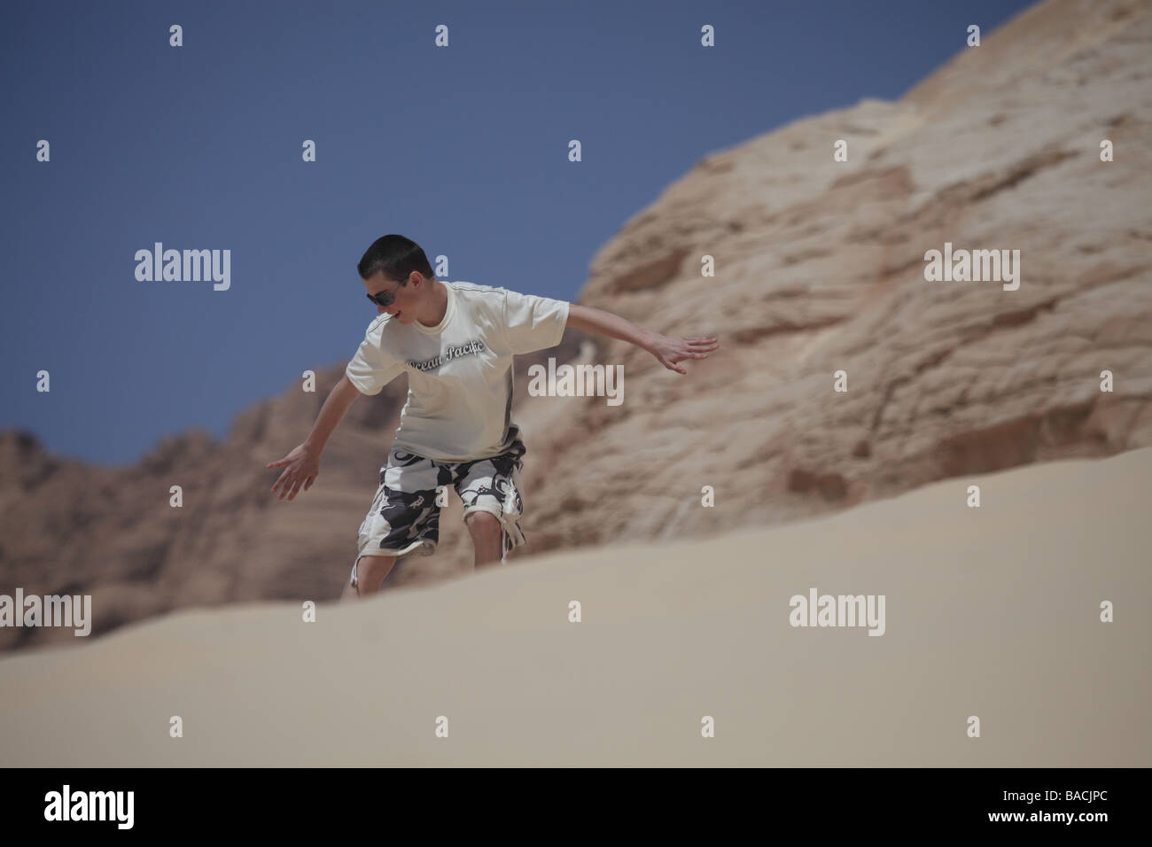 Young teenage boy sand boarding competently down a dune in the sinai desert egypt Stock Photo