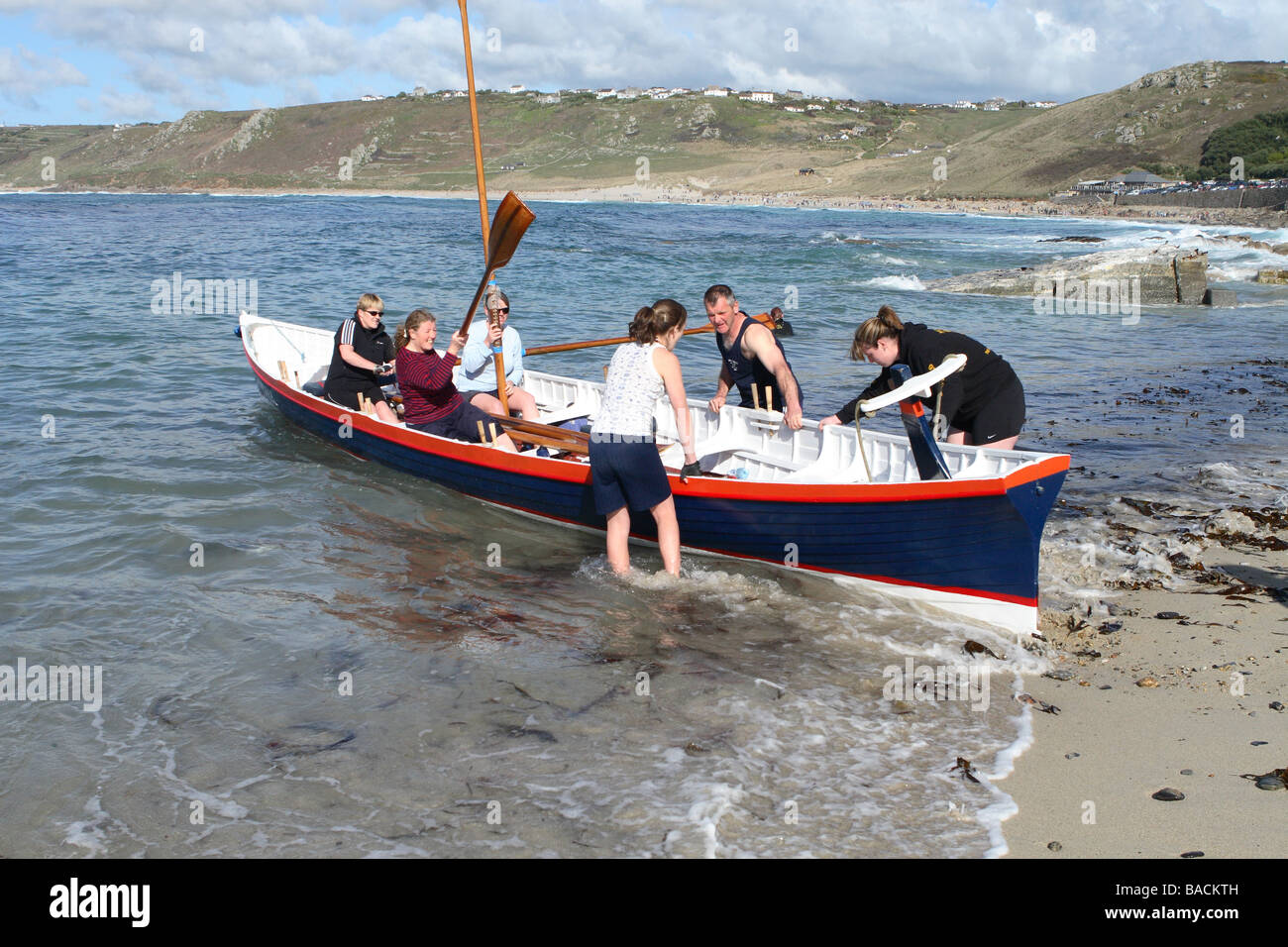 Sennen Cornwall the crew of the Cape Cornwall Pilot Gig boat prepare to launch from the sandy beach at Sennen Cove UK Stock Photo