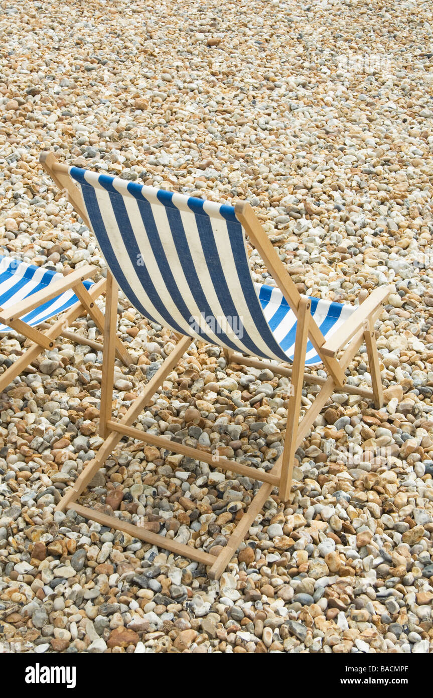 Blue and white striped deck chairs on pebble beach at Lyme Regis Stock Photo
