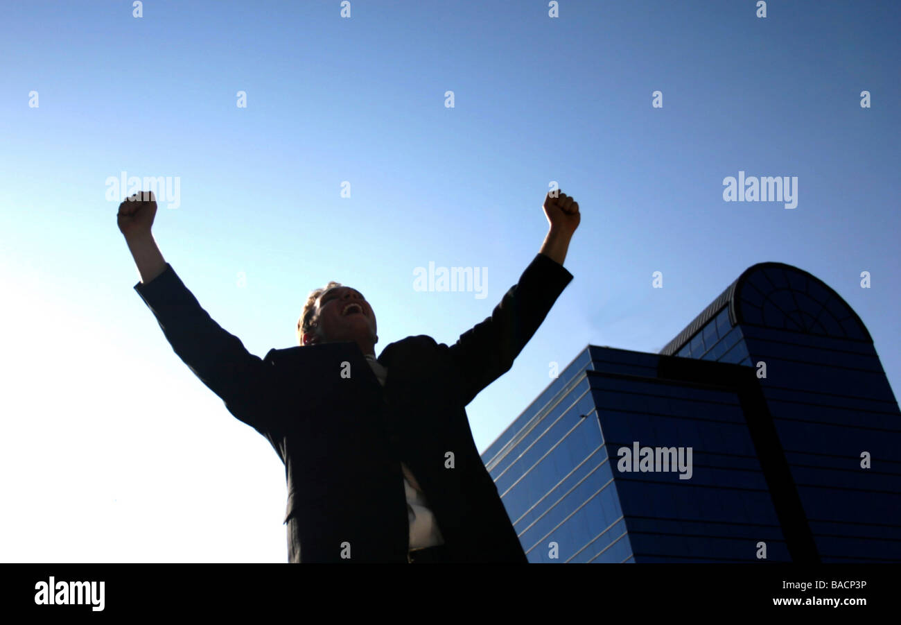 Business man holding up his arms in victory with a blue office building ...
