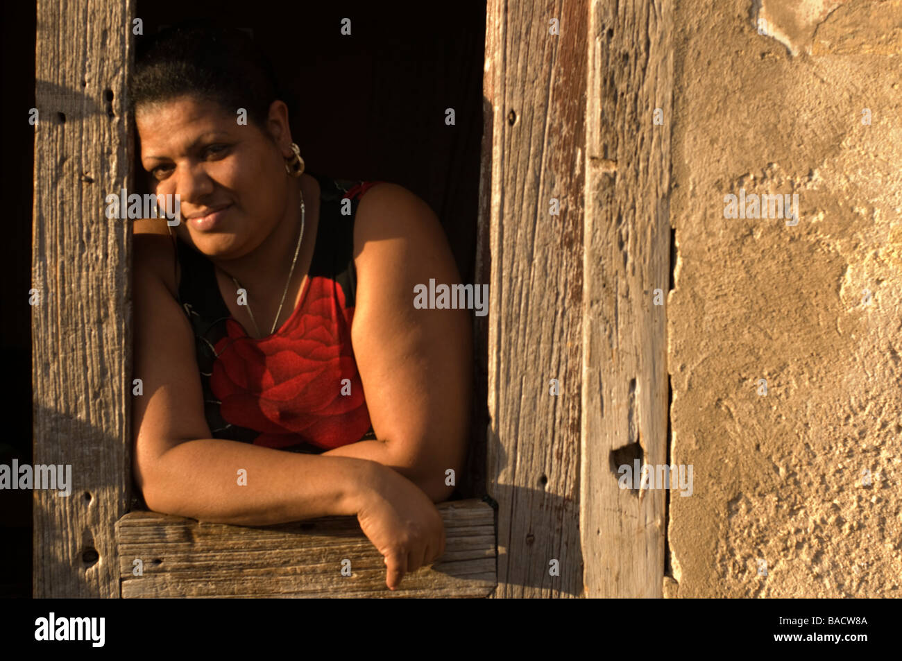 Woman leaning out of doorway at sunset in Trinidad, Cuba. Stock Photo