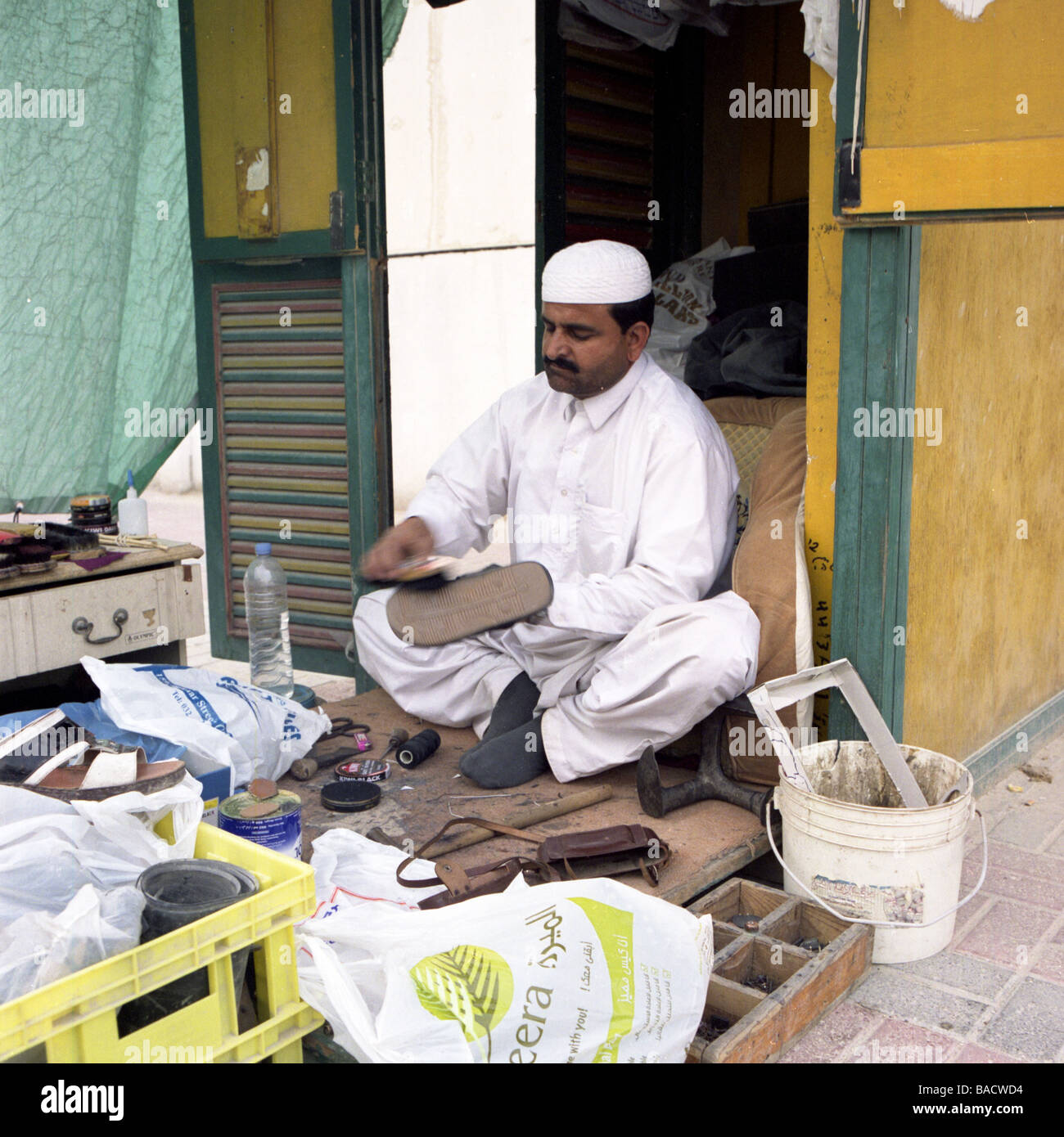 An Asian shoe repair and shoe shine man at his on street booth in Doha Qatar Stock Photo