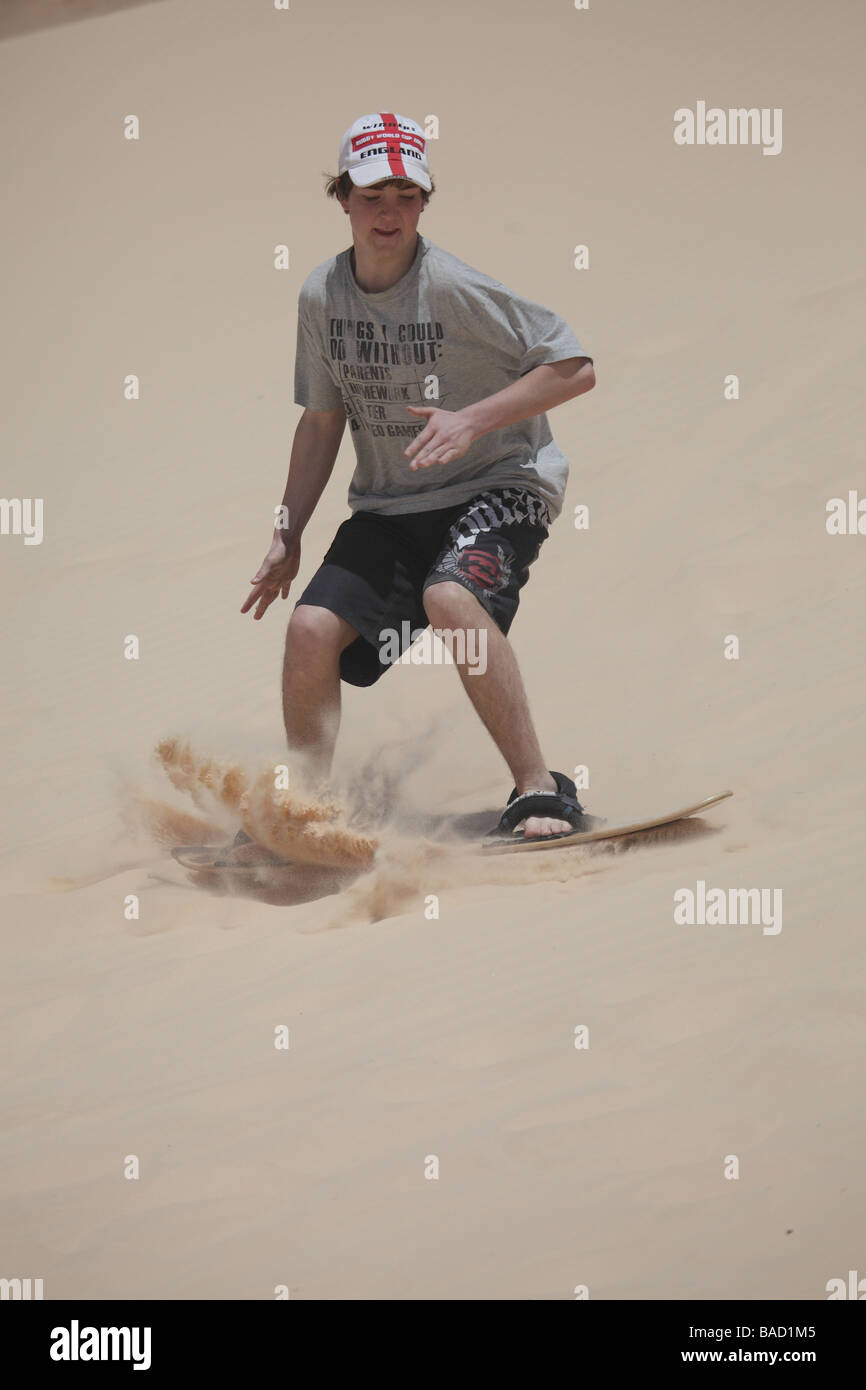 Young teenage boy sand boarding competently down a dune in the sinai desert egypt Stock Photo