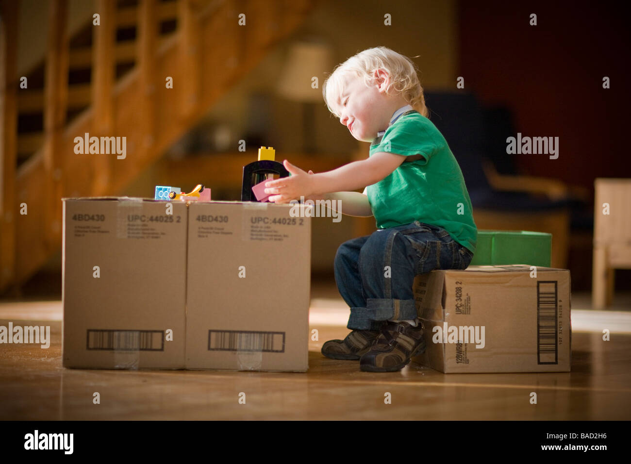 Toddler playing with toys on cardboard boxes Stock Photo