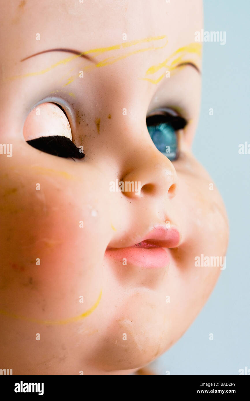 A well used baby doll face with one eye closed. Stock Photo