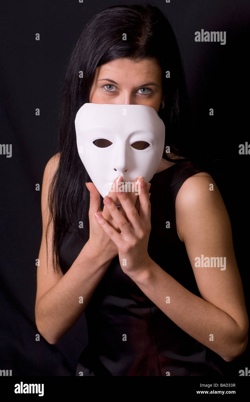 Beautiful young woman holding a white mask in front of her face Stock