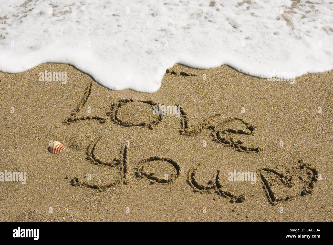 Sea washing away the words I Love You written in the sand Stock Photo