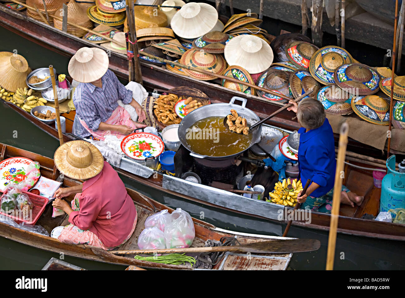 Selling hats and fried bananas from canoes at Damoen saduak floating market Bangkok Thailand Stock Photo
