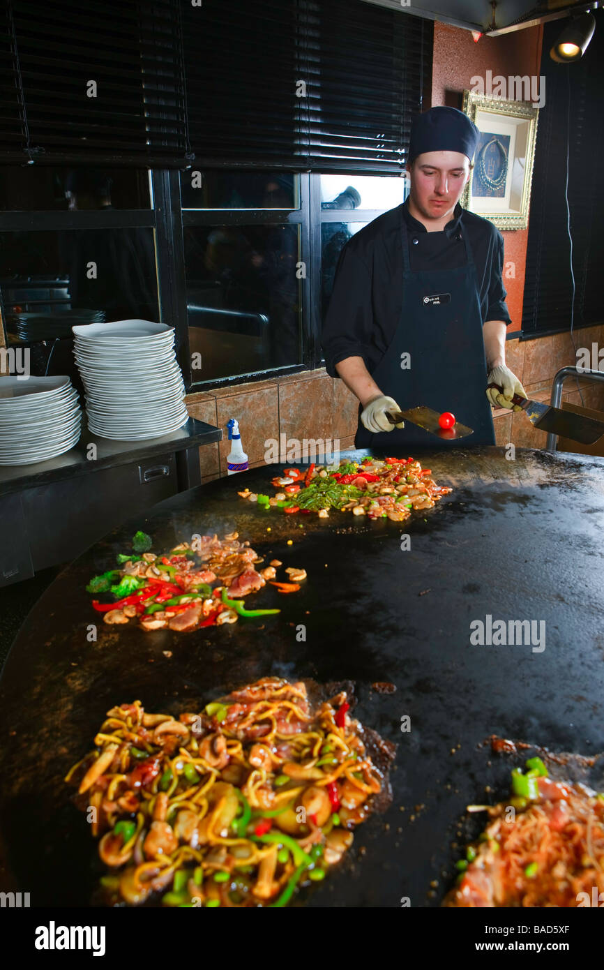 Chef performing with utensils and food while preparing meals at the Mongolie Grill World Famous Stirfry Restaurant in Whistler. Stock Photo