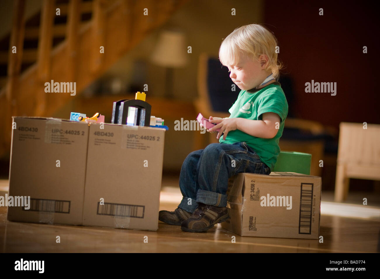 Toddler playing with toys on cardboard boxes Stock Photo