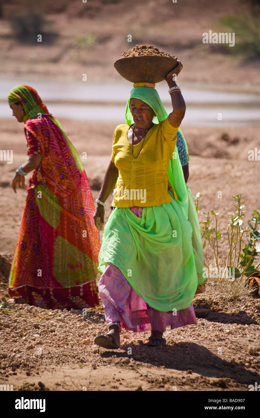 Woman labourer carrying container of soil on her head, Keechen, near Phalodi, Rajasthan, India Stock Photo