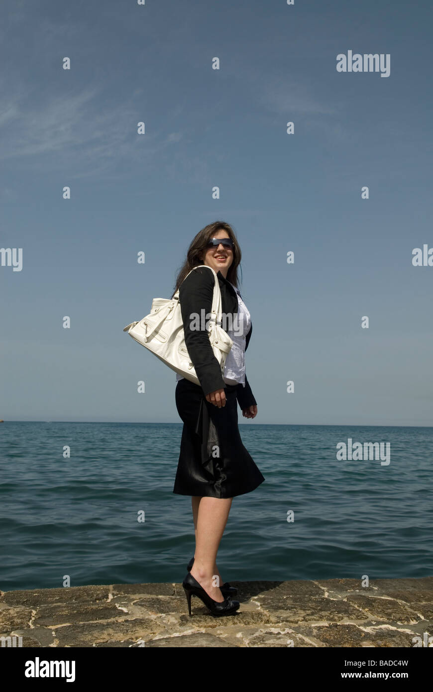 Business woman standing by the sea carrying a handbag Stock Photo