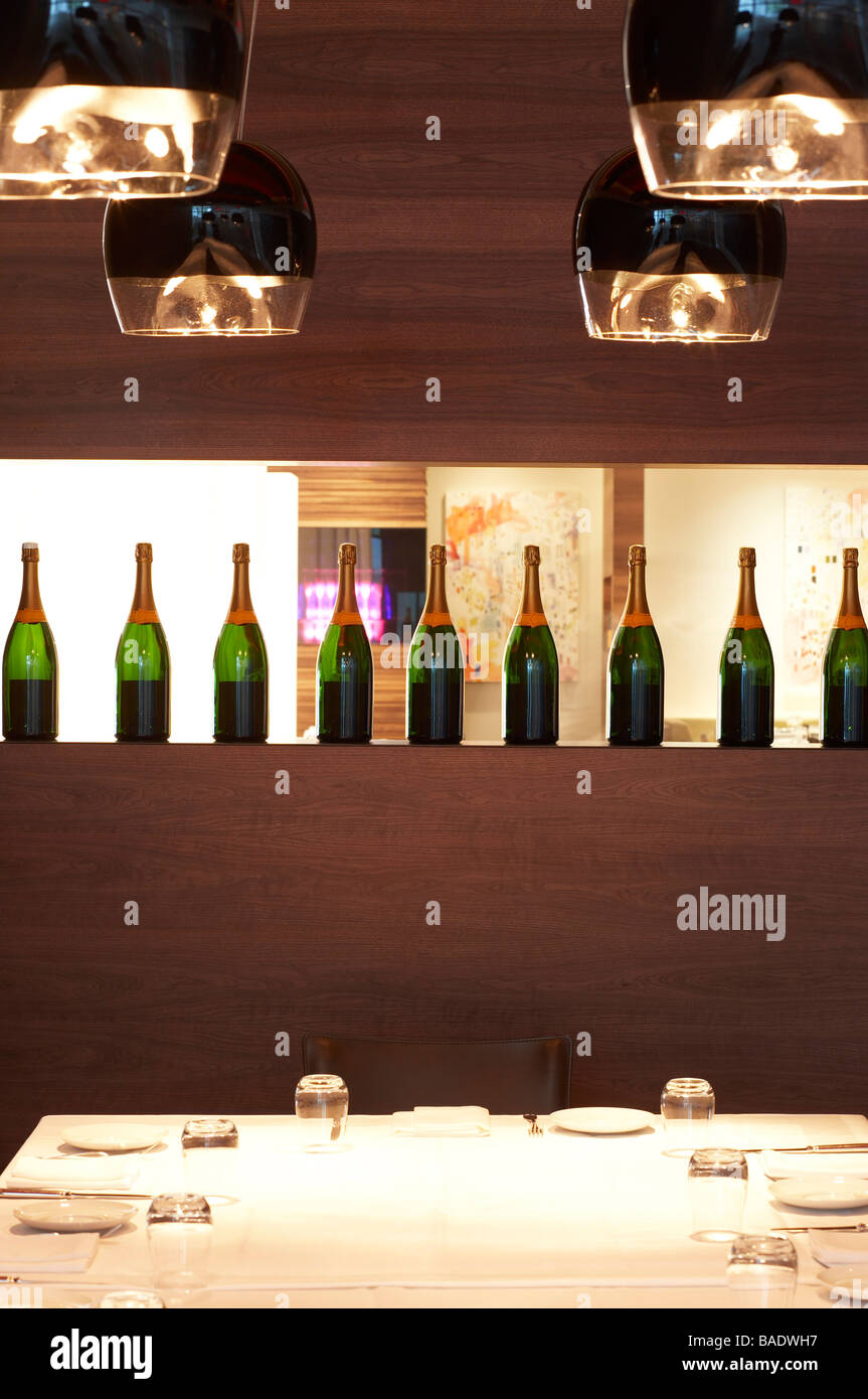 Row of Wine Bottles and Table Setting in Restaurant Stock Photo