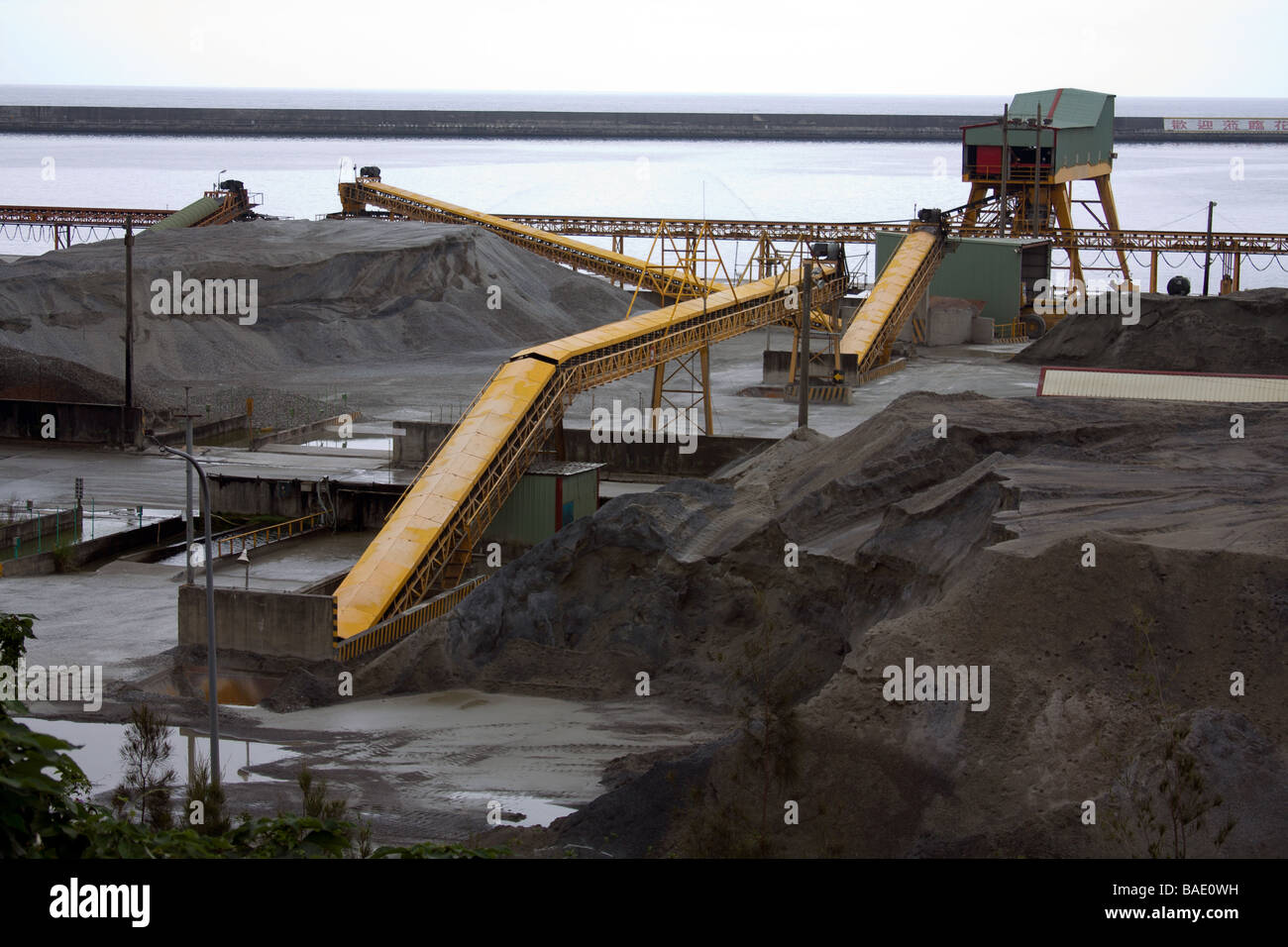 Open yard stacker, mineral and gravel storage at bulk cargo terminal area, warehouse zone, Hualien Port, Taiwan Stock Photo