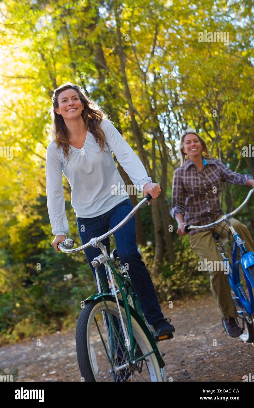 Two Women Riding Bicycles through Forest Stock Photo