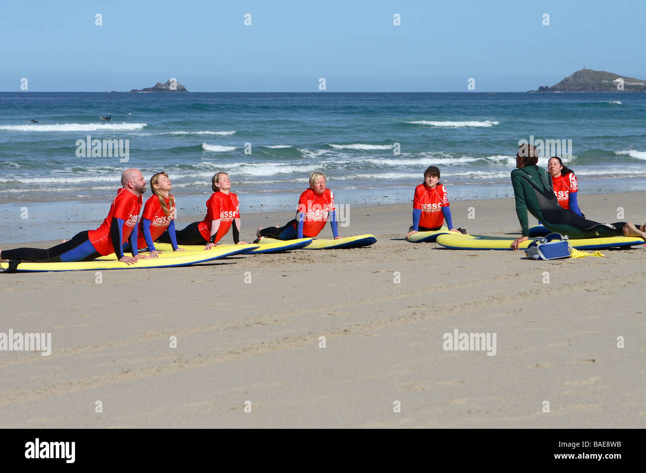 Sennen Cove beach Cornwall people learning to surf with a surf school on the sandy beach on the Atlantic coast in April Stock Photo