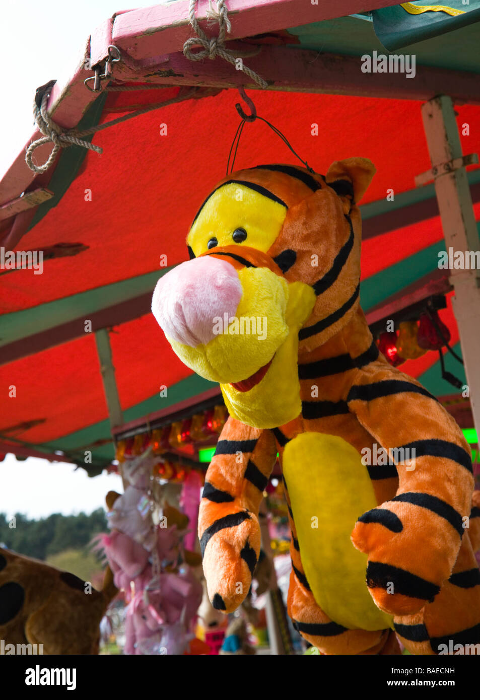 Disney 'Tigger'. A stuffed cuddly toy tiger, offered as a prize, hanging from a stall at a fairground. UK. Stock Photo