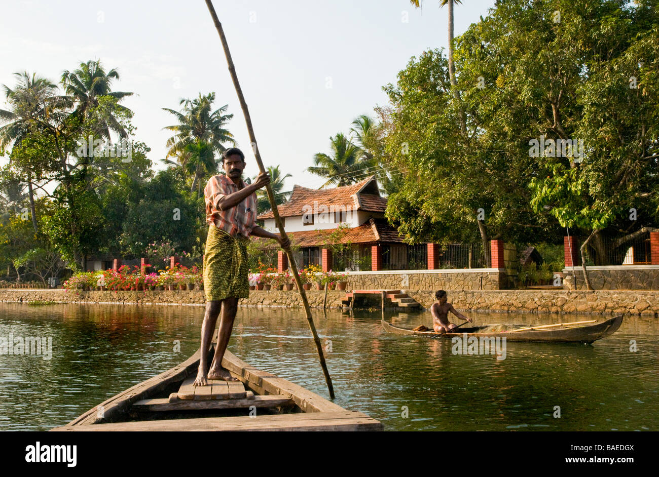 Ferryman punting a 'vallam’(country boat) taking guests over to Philipkutty’s Farm a smart homestay and spice farm on Kerala's Backwaters, India Stock Photo