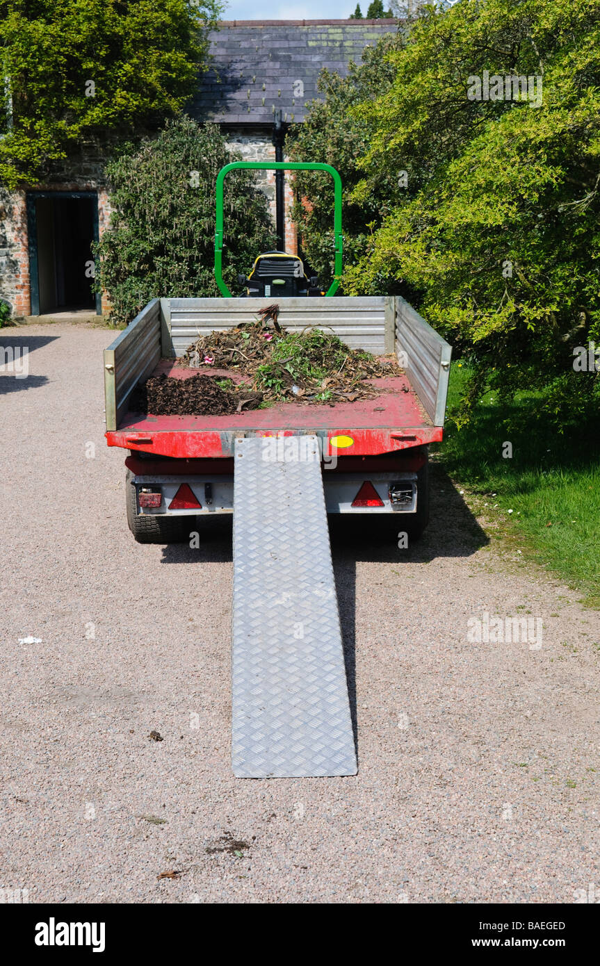 Tractor and trailer parked up with small amount of weeds/garden waste in trailer and ramp for loading and unloading Stock Photo