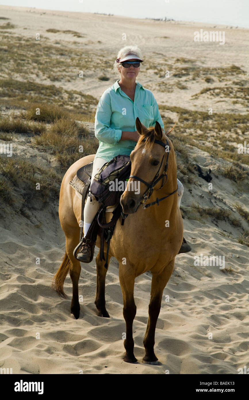 MEXICO Todos Santos Woman riding horse with western saddle on the beach along Pacific Ocean Playa La Cachora Stock Photo