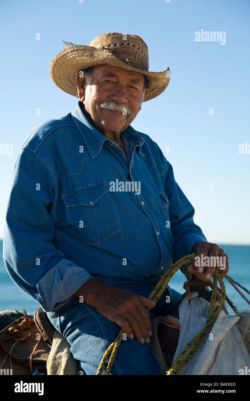 MEXICO San Jose del Cabo Portrait of Mexican man on horseback wearing cowboy hat and riding horse on beach Stock Photo