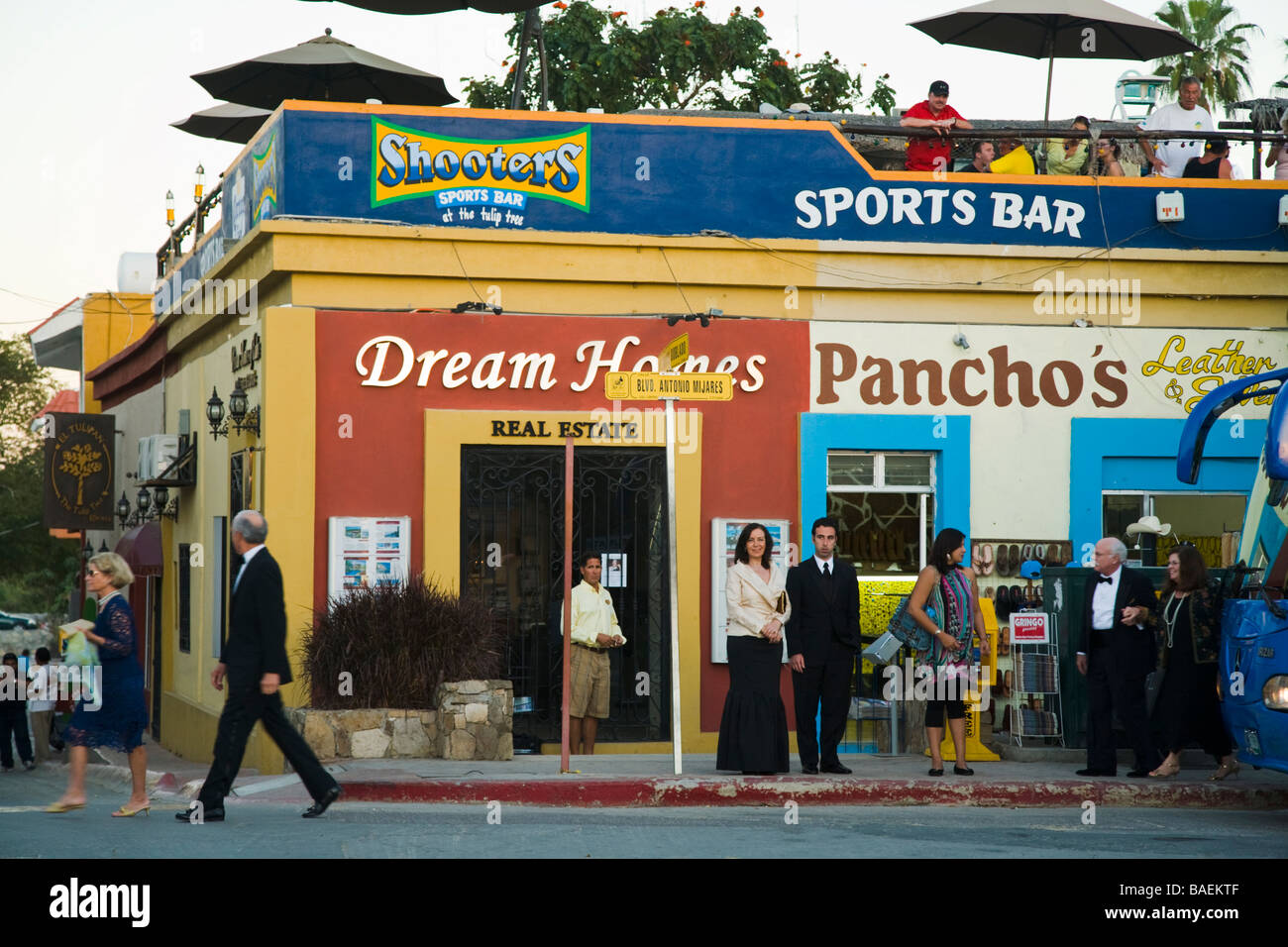MEXICO San Jose del Cabo Wedding guests in formal clothing walk past sports bar and stores in Mexican town Stock Photo