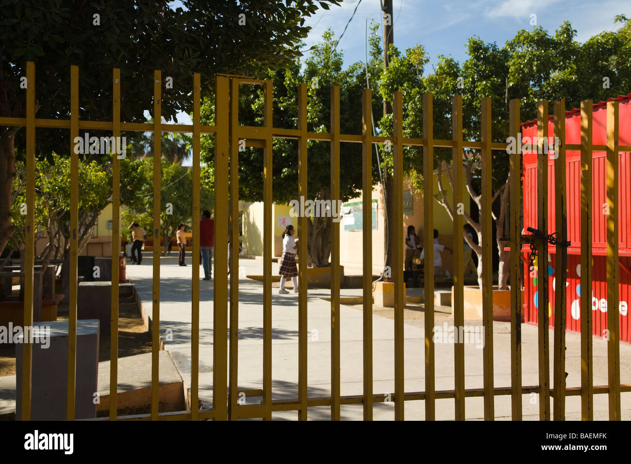 MEXICO La Playita Mexican elementary school children walk across courtyard between school buildings secured by iron fence Stock Photo
