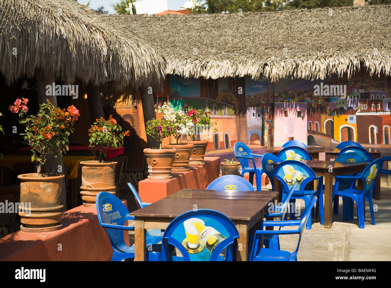 MEXICO La Playita Tables and chairs in outdoor dining area for Tommy s Barefoot cantina restaurant painted mural on wall Stock Photo