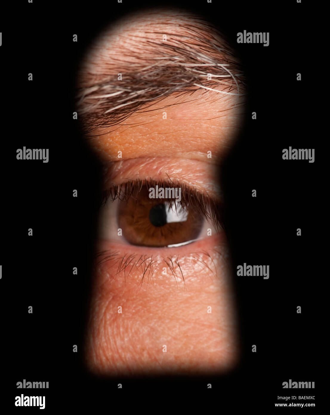 male eye peeking in keyhole Stock Photo