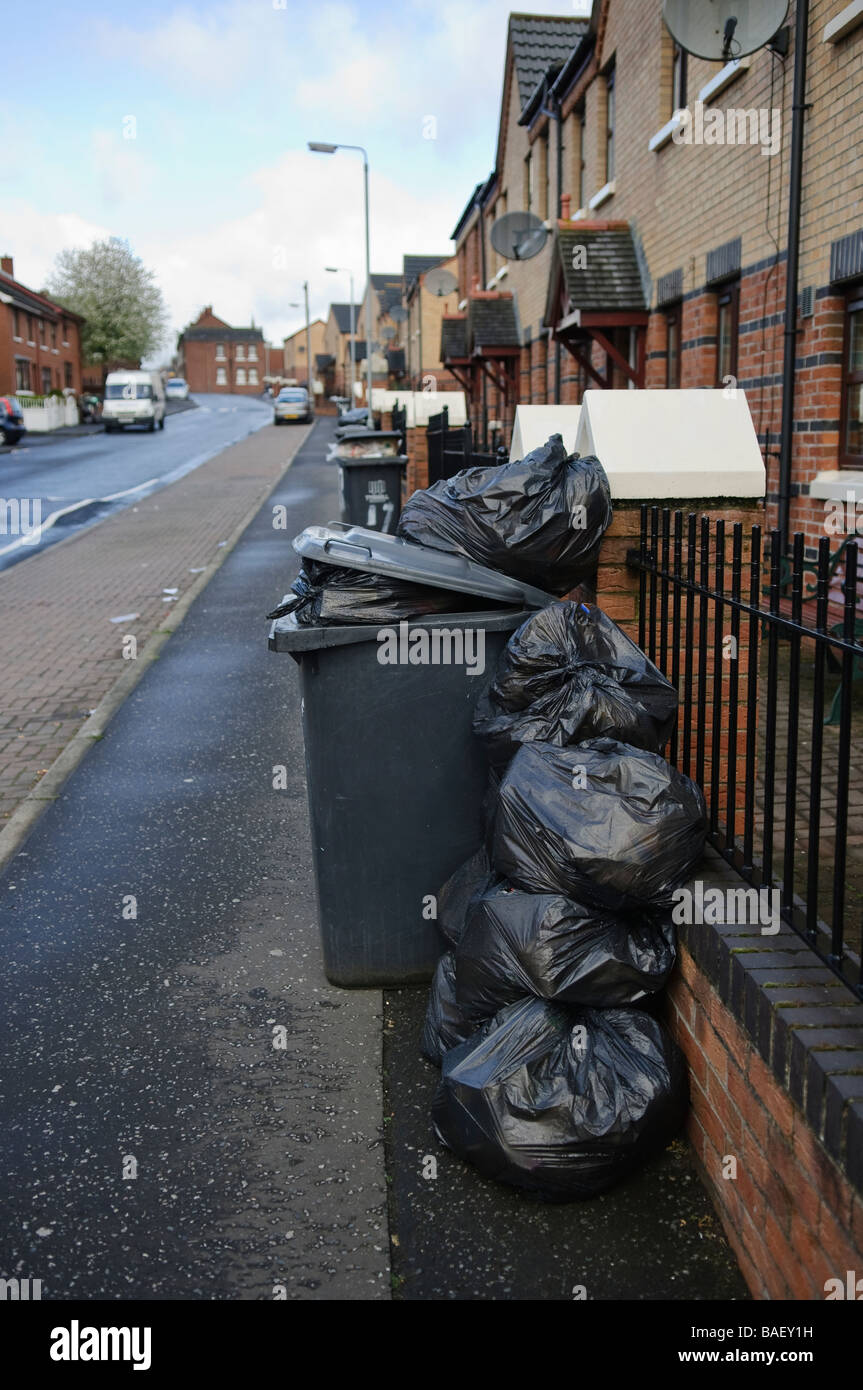 Plastic bags piled up beside an overflowing black bin ready to be collected. Stock Photo