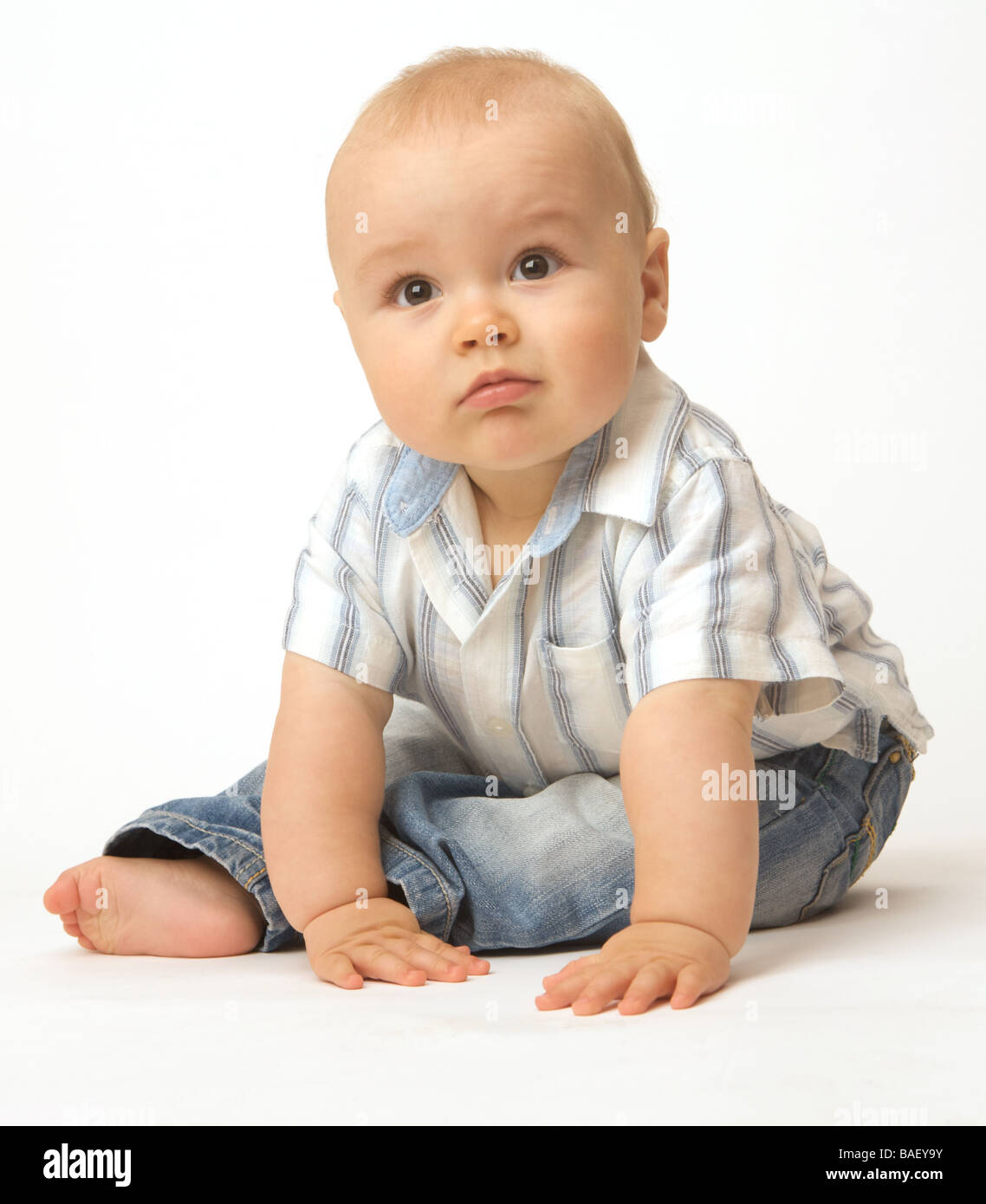 A baby leans forward on a white background whilst seated Stock Photo