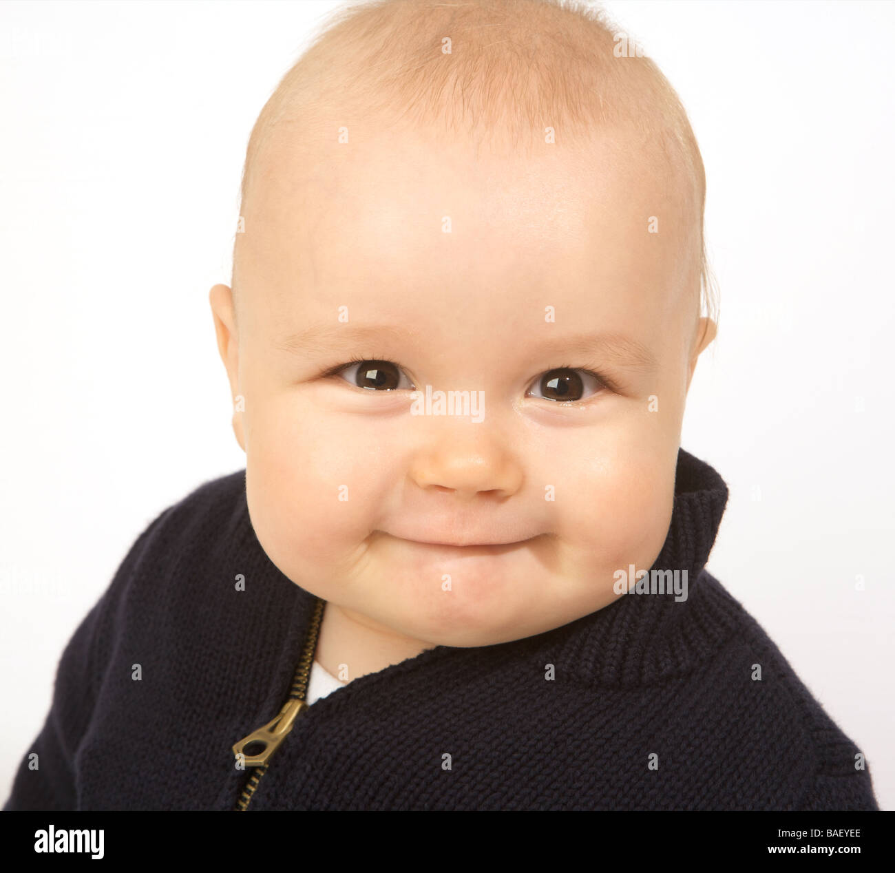 A baby smiles and chews his bottom lip on a white background Stock Photo