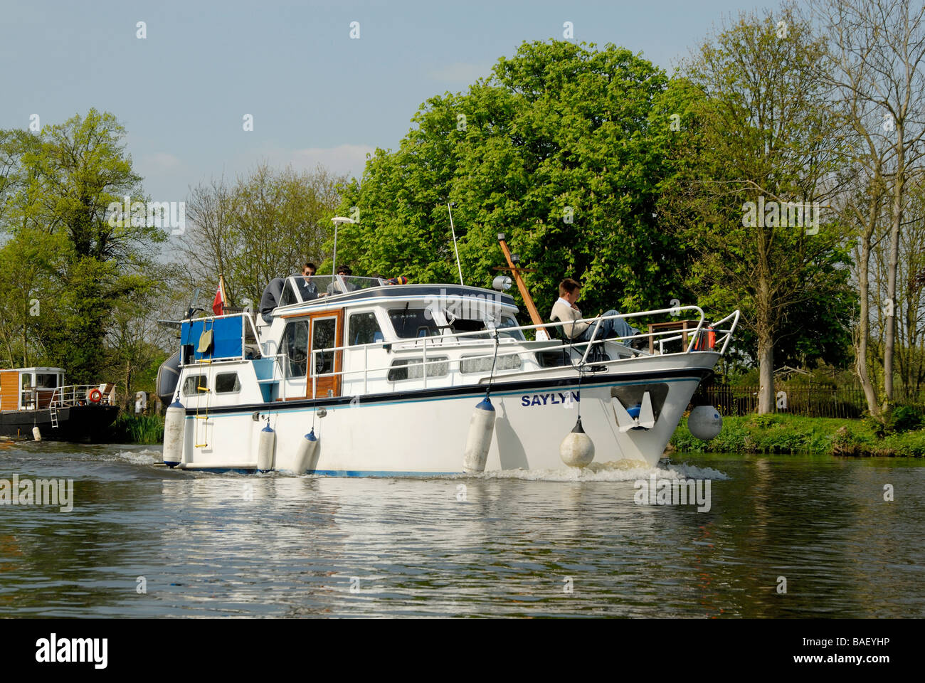 Steel hulled motor cruiser with young men at the helm and on deck, River Thames below Chertsey, Surrey, England Stock Photo