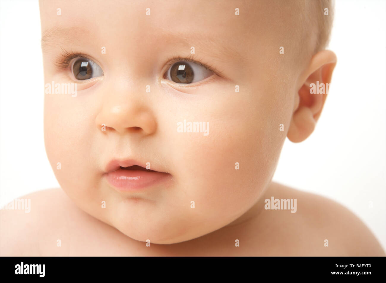 A baby looks against a white backdrop Stock Photo