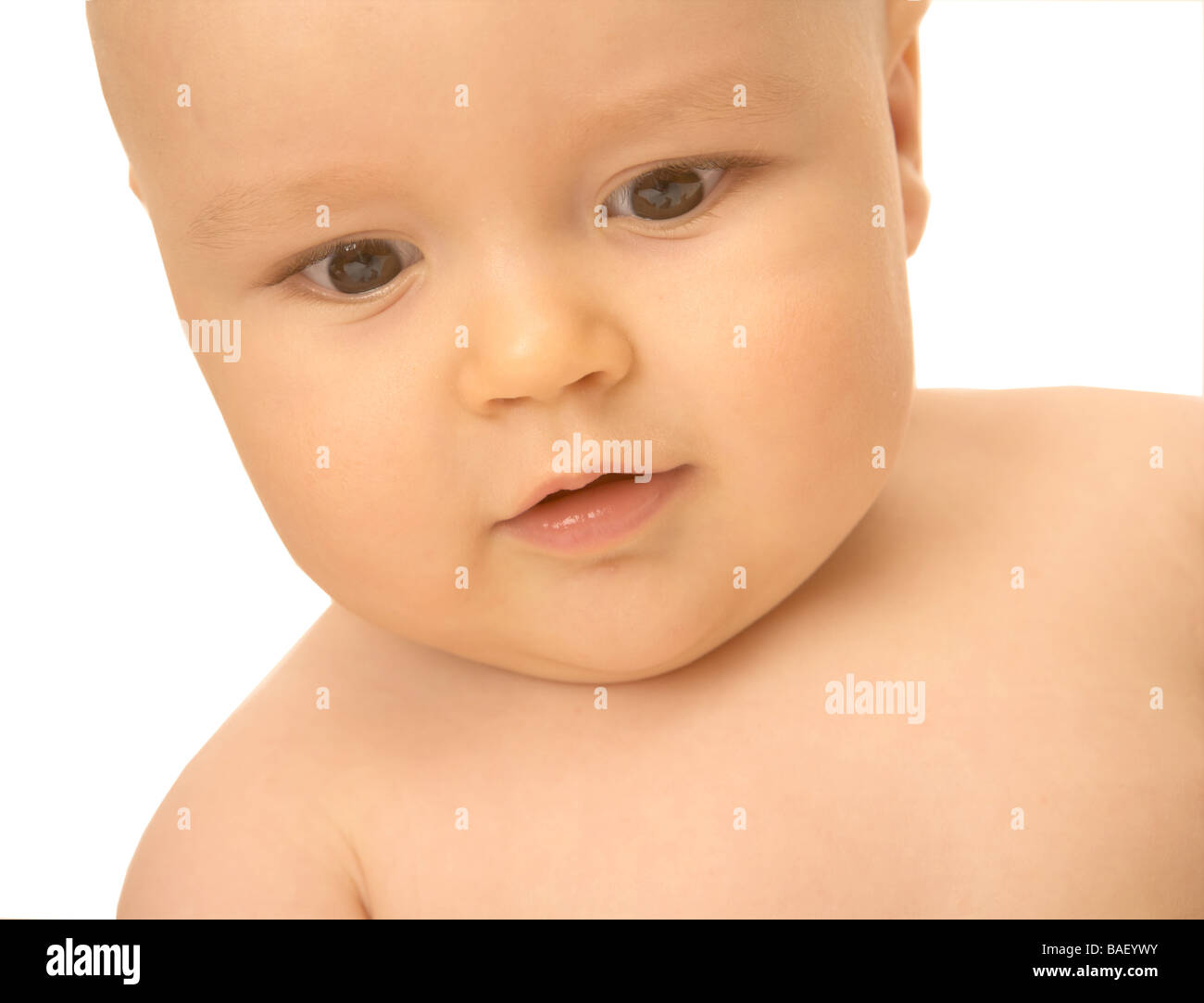 A baby looks downwards against a white backdrop Stock Photo